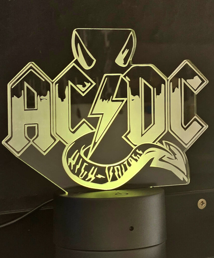 lámpara LED con el logotipo de la banda de hard rock AC/DC. El diseño incorpora el icónico logotipo de la banda, que incluye las letras "AC/DC"